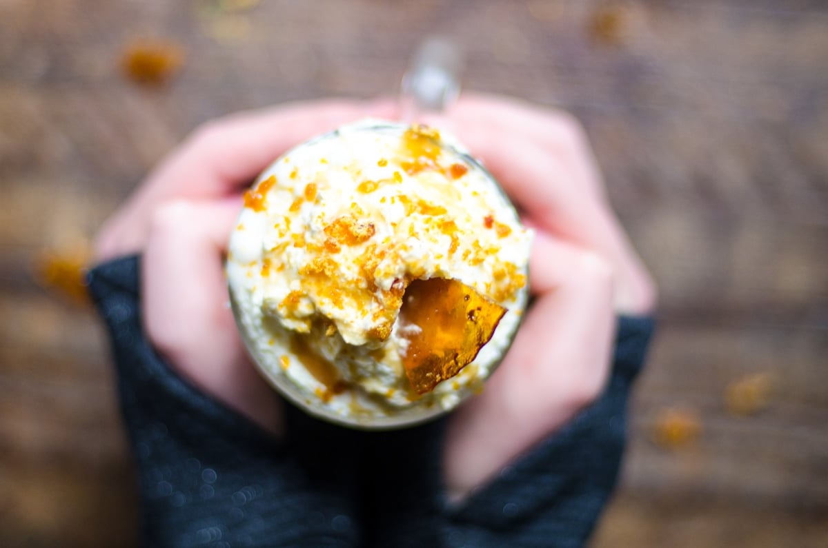 Two hands wrapped around a mug of homemade caramel brulee latte.