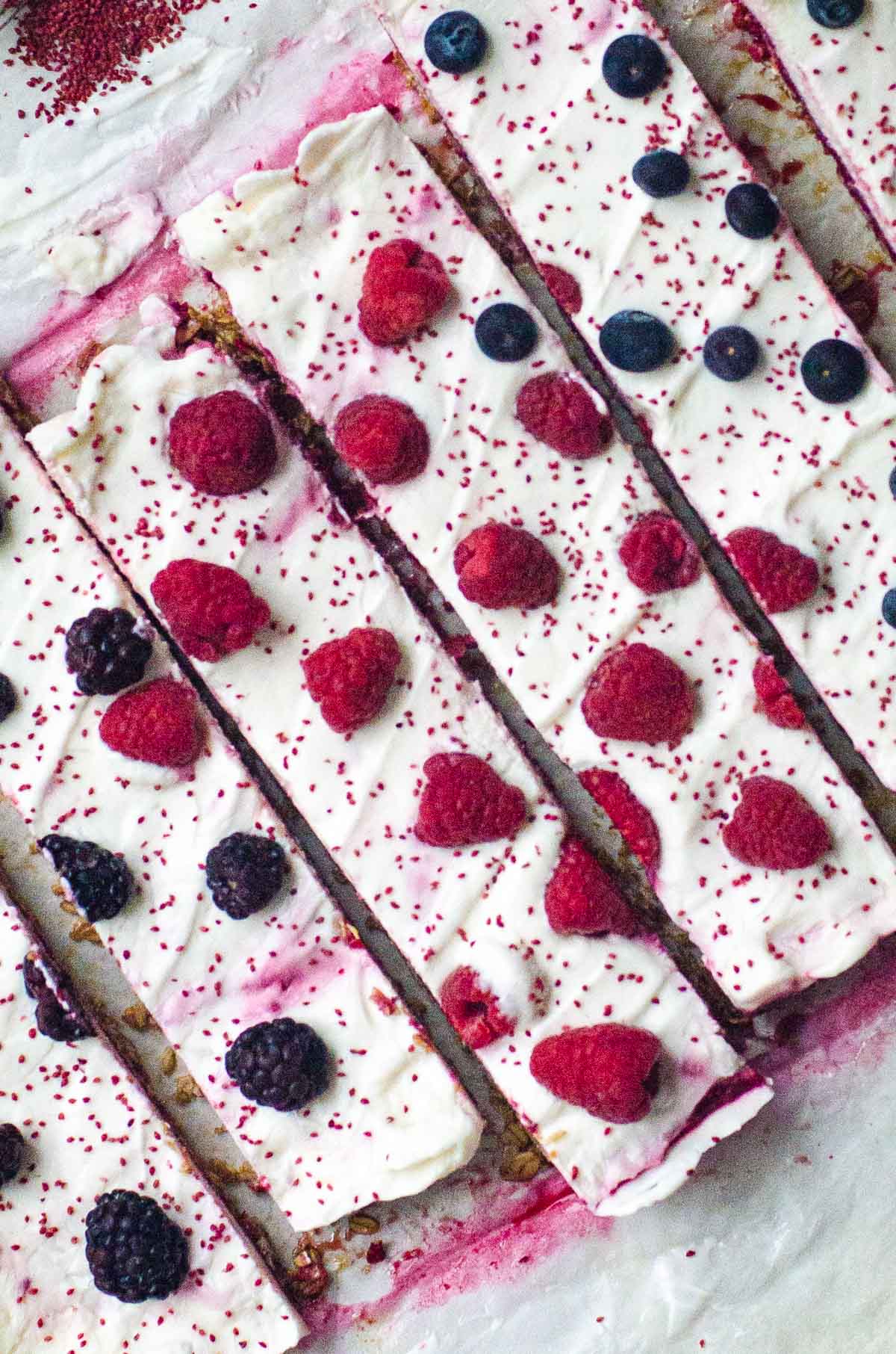 Overhead view of sliced frozen yogurt bars with fresh berries on top.