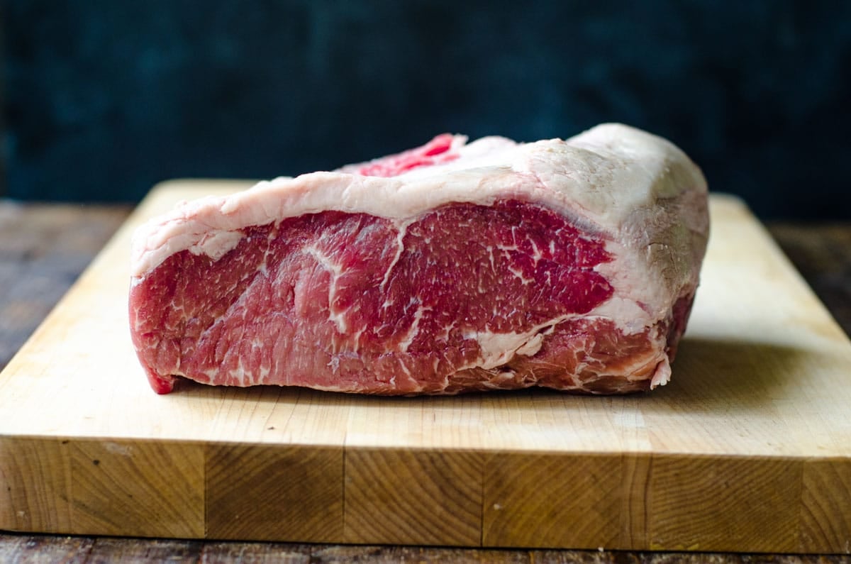 New York Strip loin on a cutting board showing fat cap and marbling.