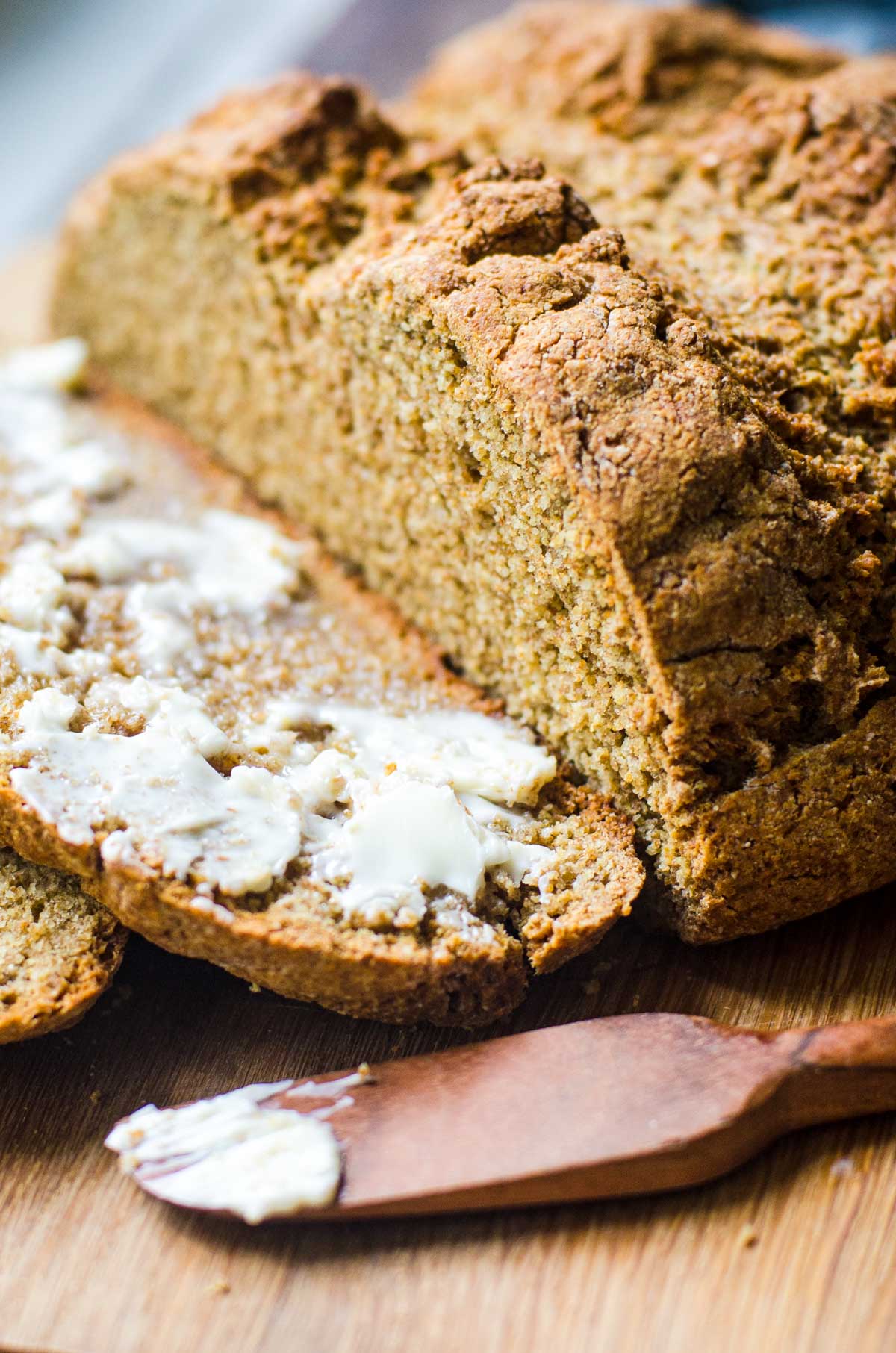 A cutting board with sliced buttered soda bread next to knife with butter.