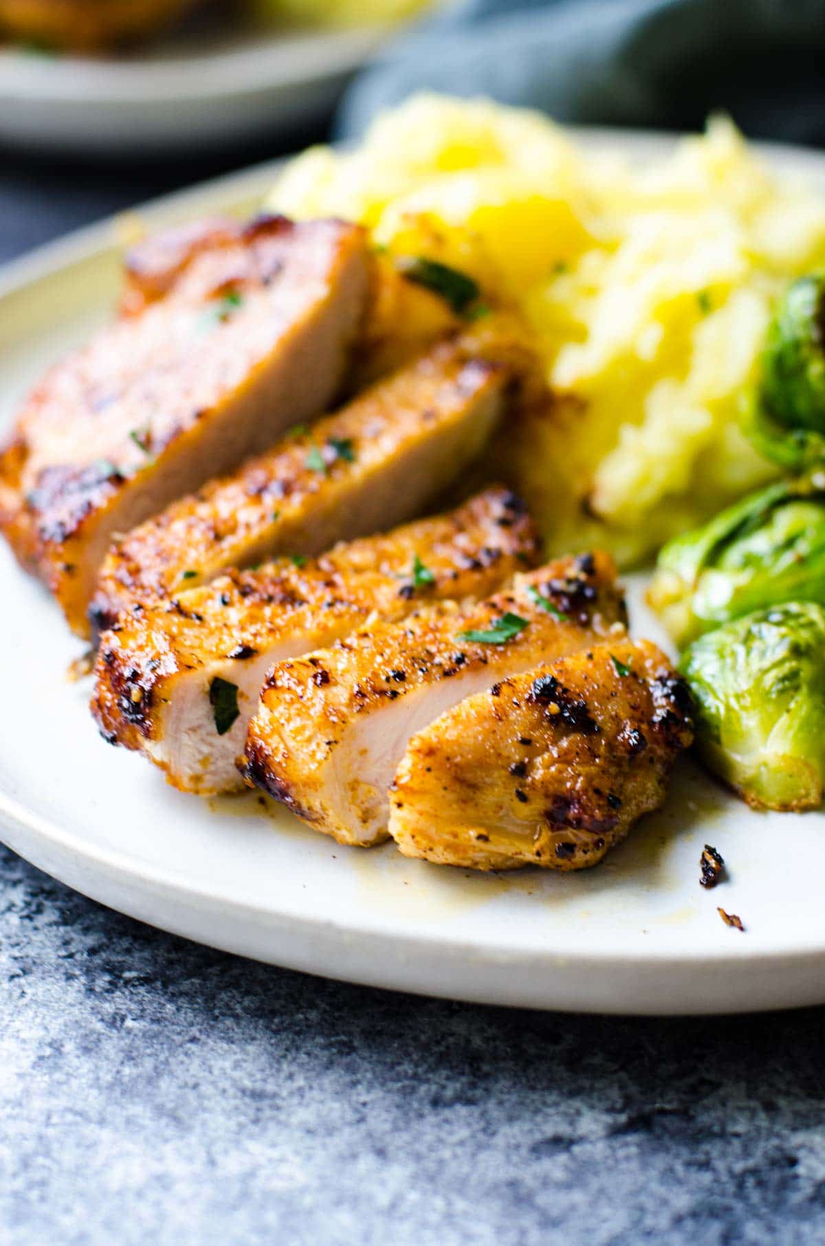 Sliced pork chops on a tan plate with side dishes.