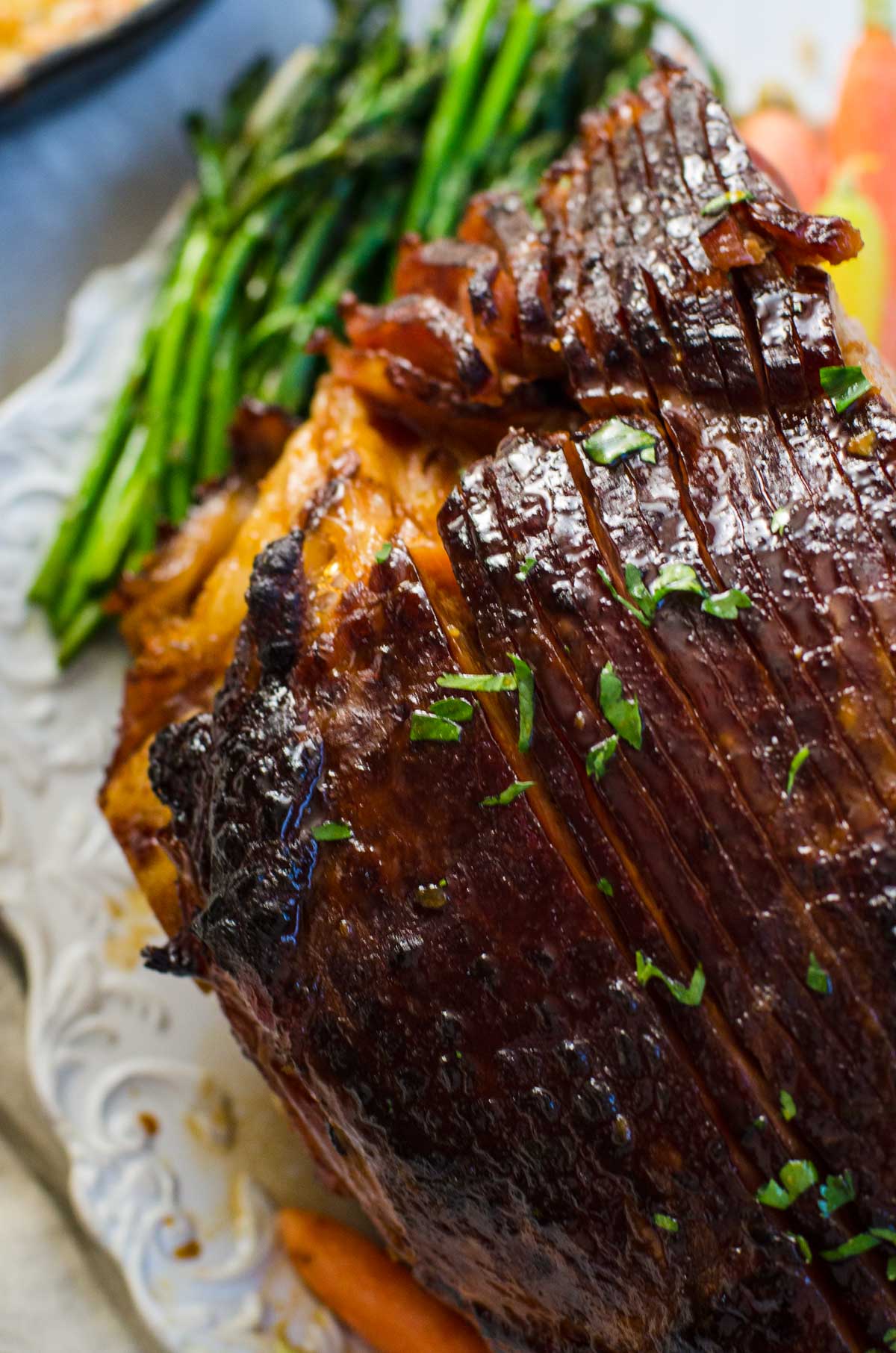 Overhead view of a plate of ham surrounded with asparagus and carrots.