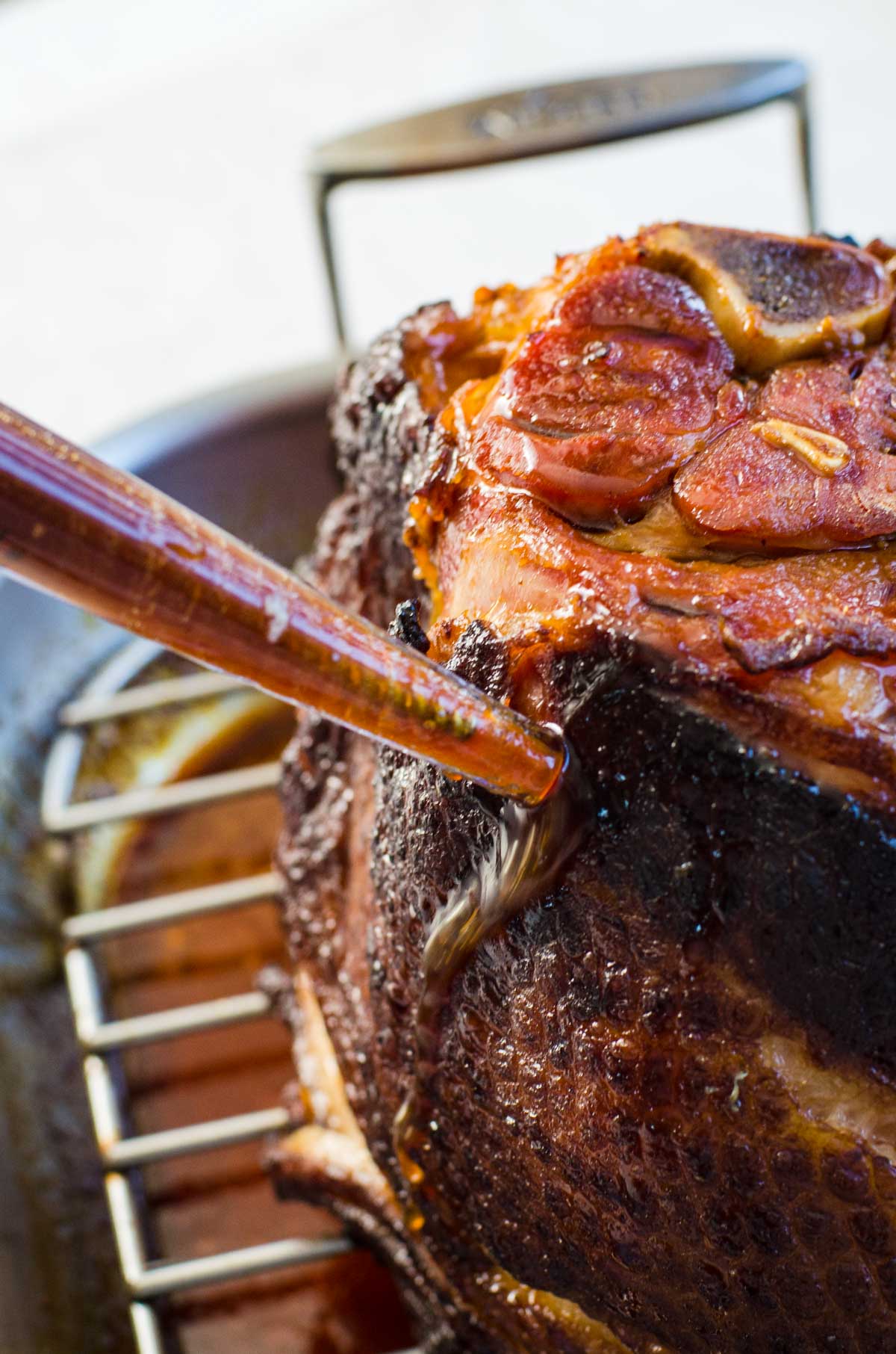 A baster putting coca cola glaze onto a ham.