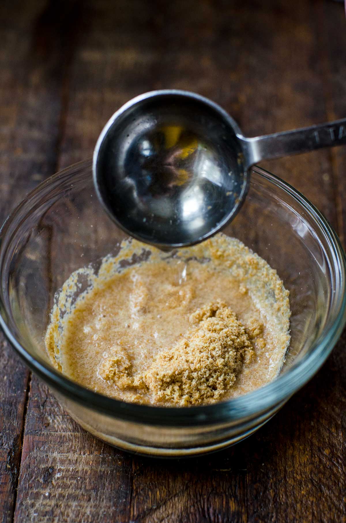 A measuring spoon pouring water into flaxseed meal.