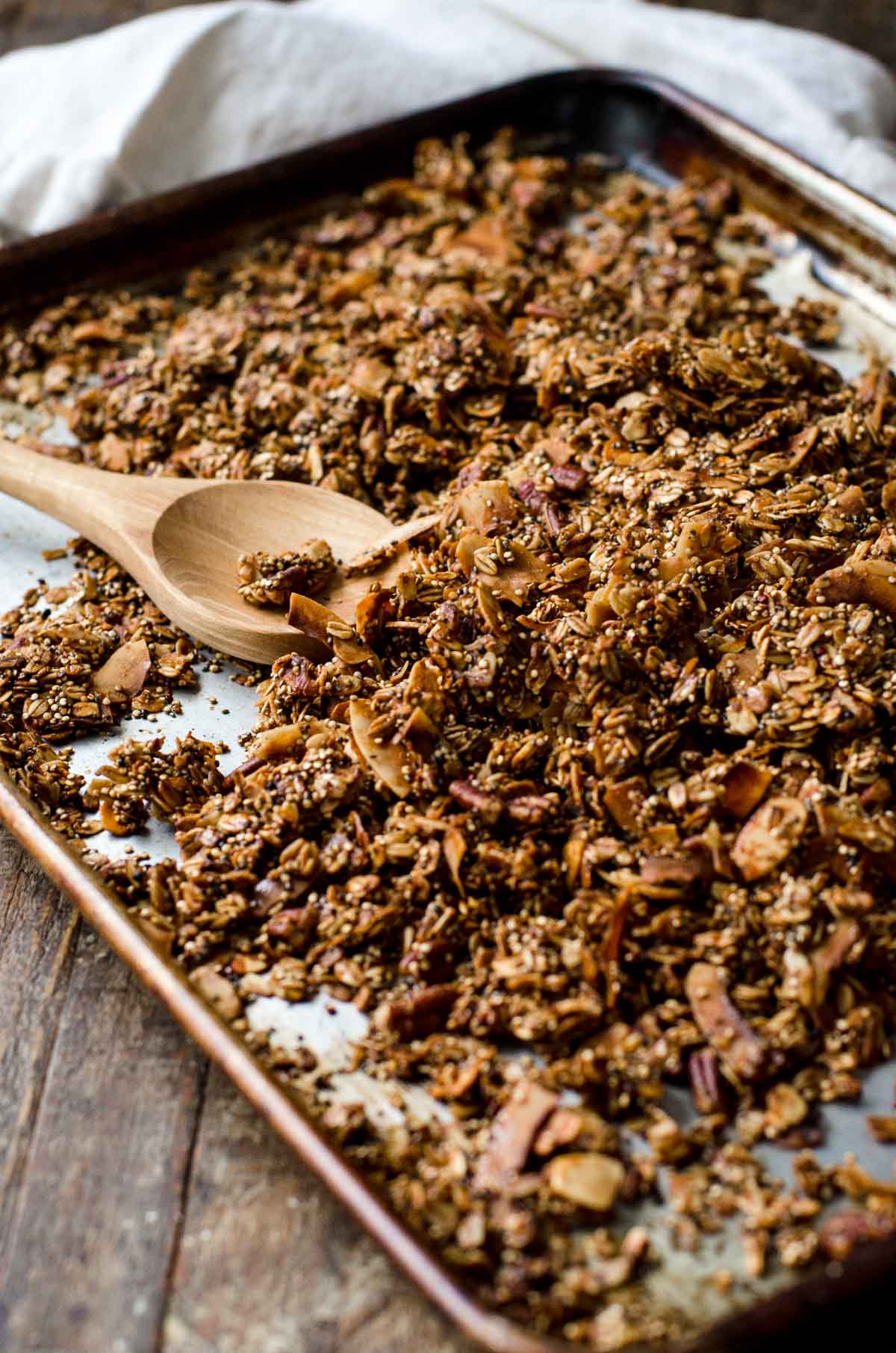 A wooden spoon scraping homemade granola into clusters.