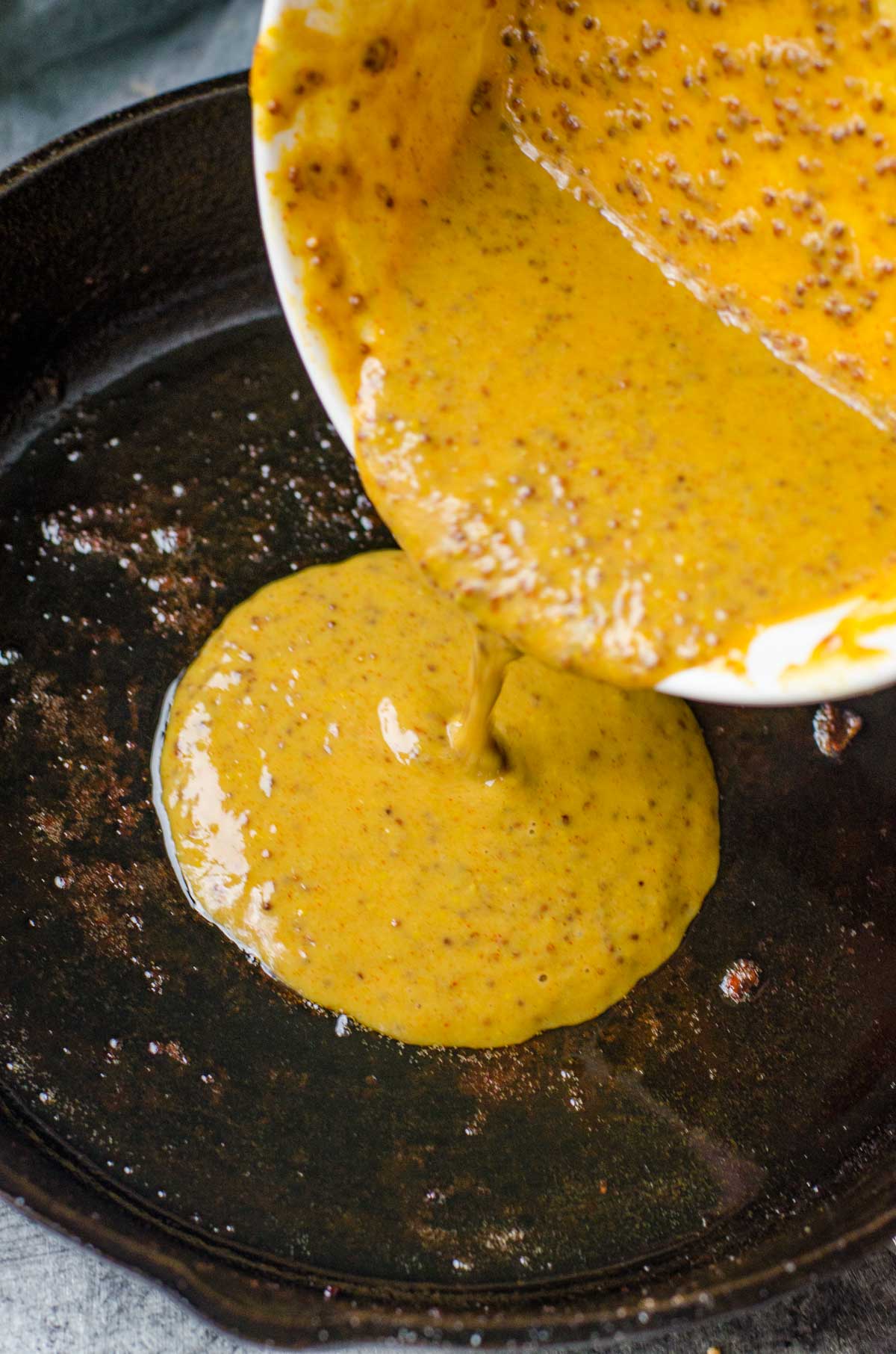 Honey mustard sauce pouring into a pan.