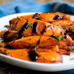 A plate of roasted carrots with balsamic glaze on them.