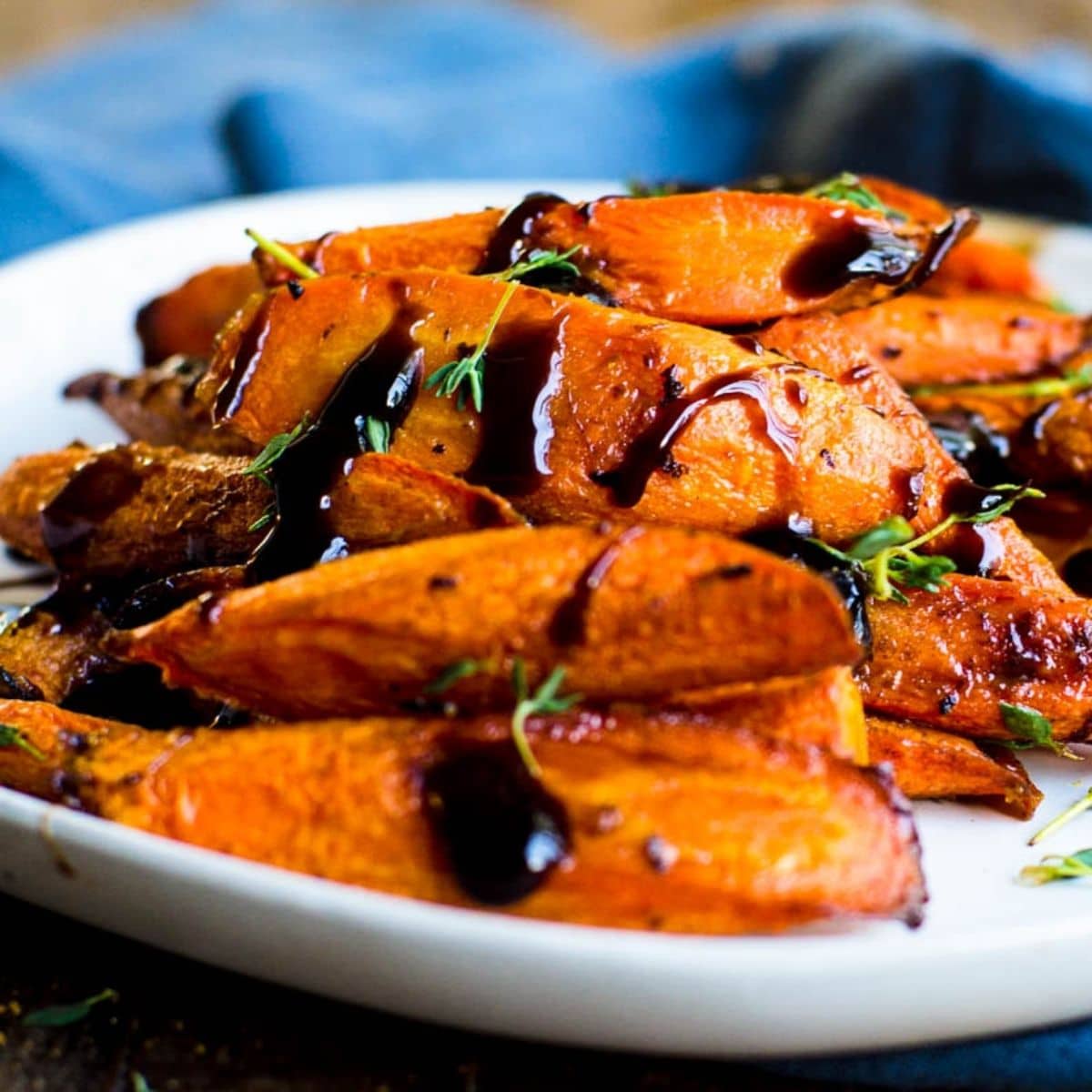 A plate of roasted carrots with balsamic glaze on them.