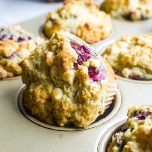 A raspberry white chocolate muffin turned sideways in the pan showing off the raspberries.