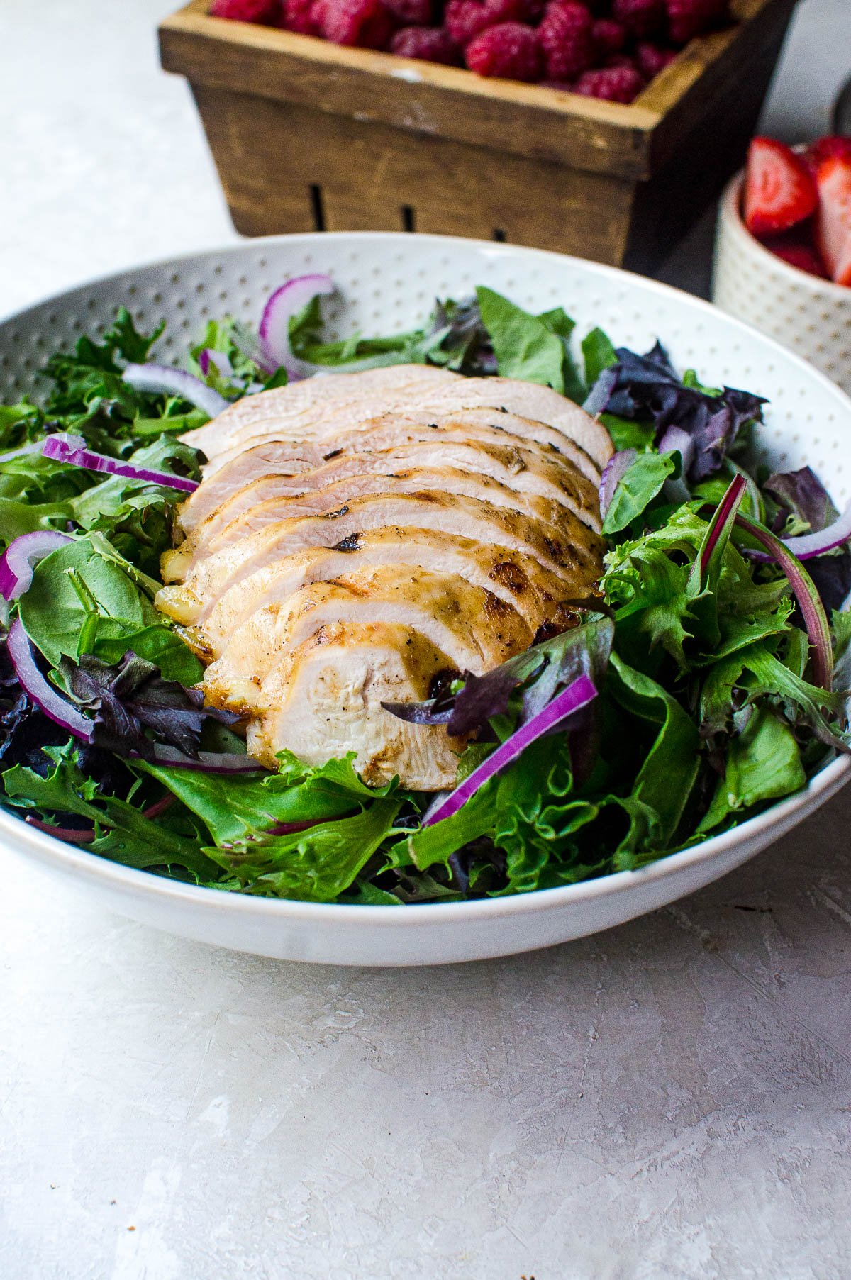 A bowl with salad greens and sliced grilled chicken.
