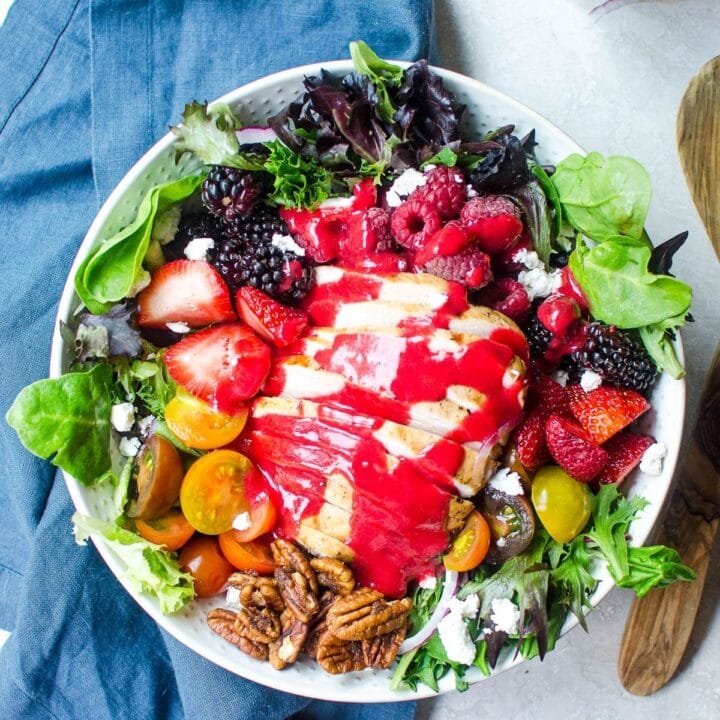Overhead view of a summer grilled chicken salad with berries and raspberry vinaigrette.