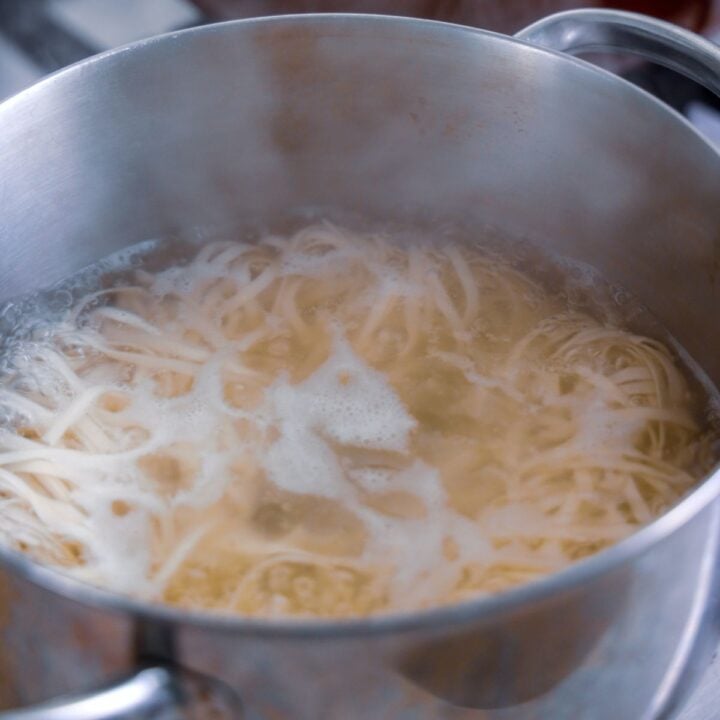 A pot of boiling water cooking pasta noodles