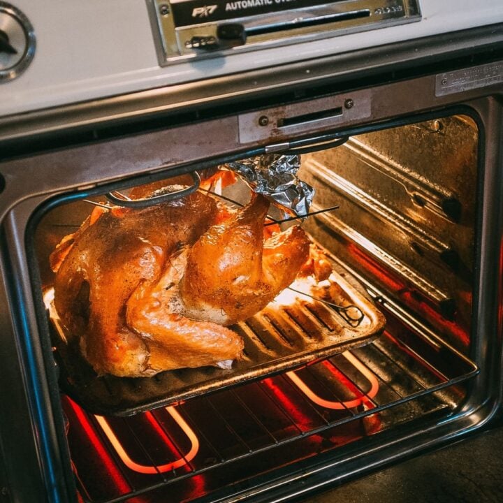 A turkey cooking in a open oven with hot heating elements.